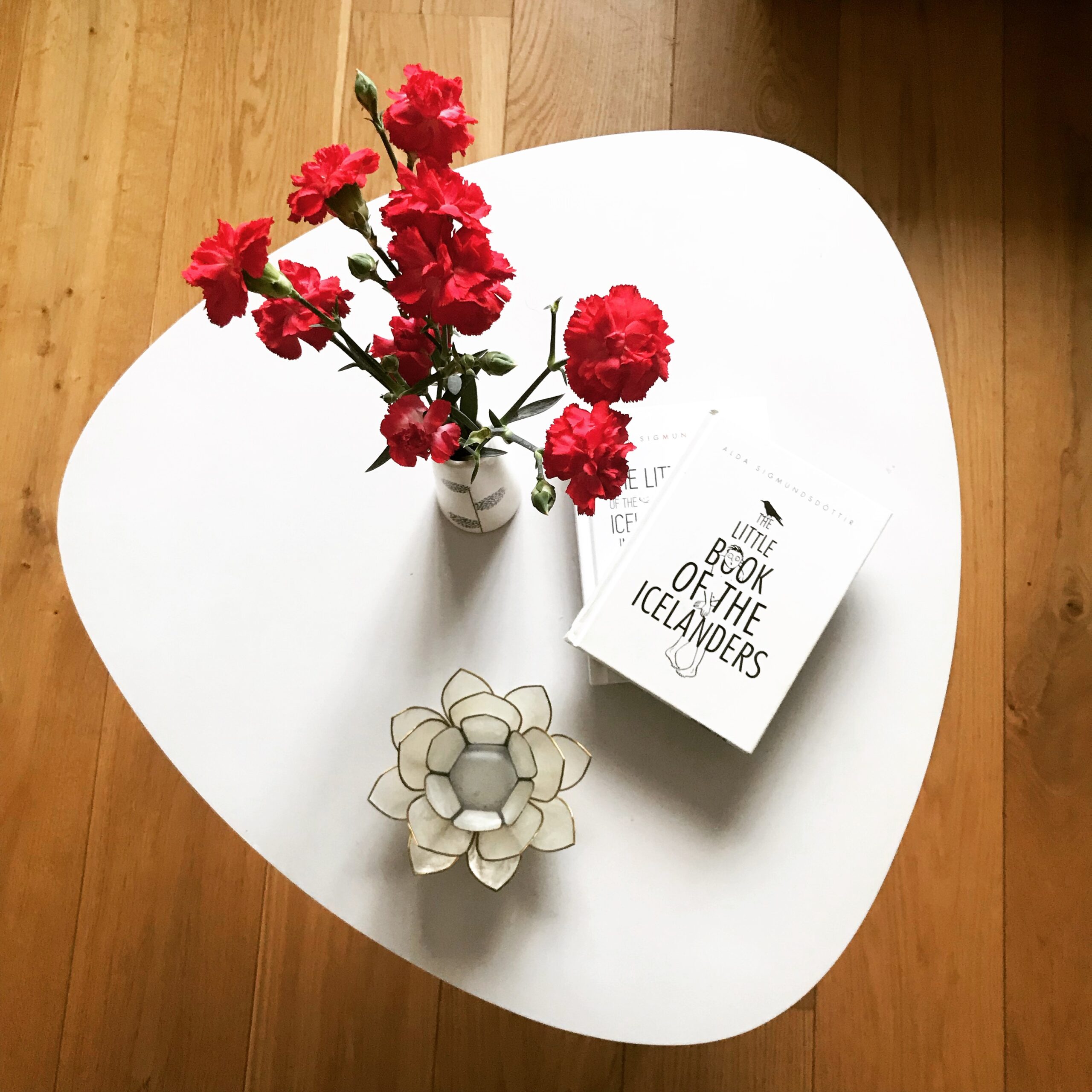 Copy of The Little Book of the Icelanders on a table with flowers